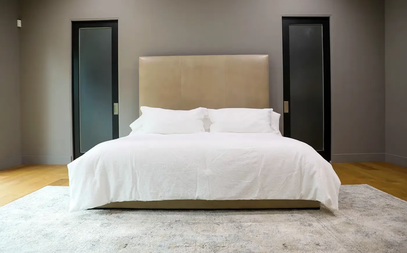 Modern bed with beige headboard, white bedding and gray accents