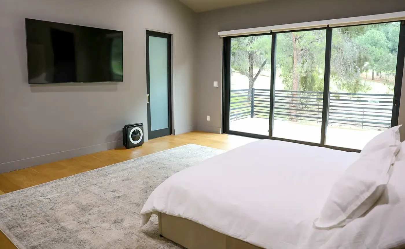 Modern bedroom with white bed, large rug and wall-mounted TV