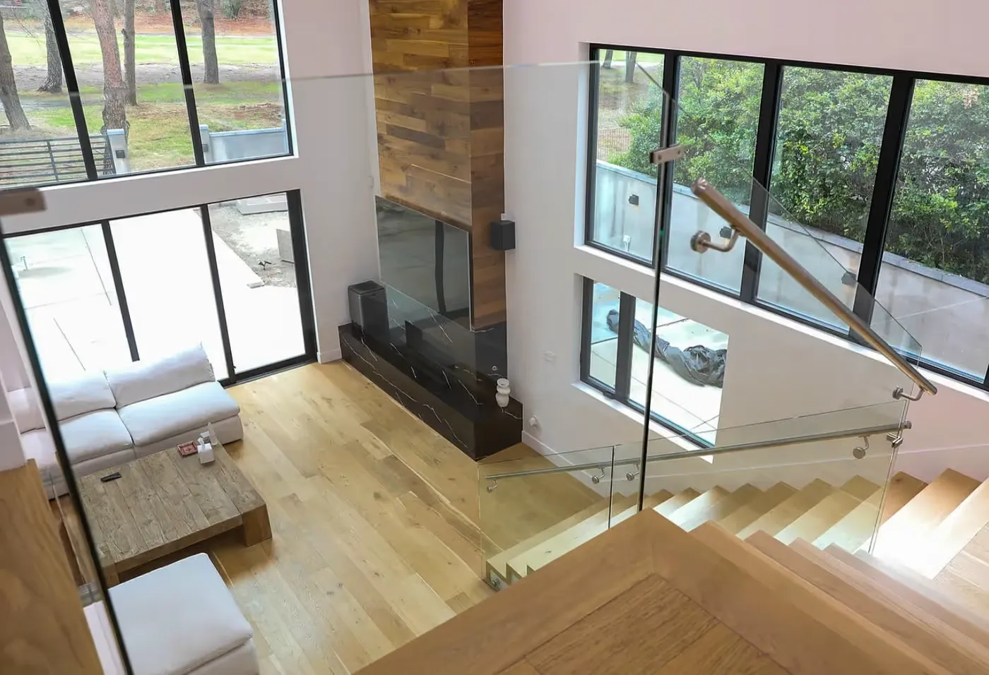 Modern living room with wooden floors, glass staircase and open layout