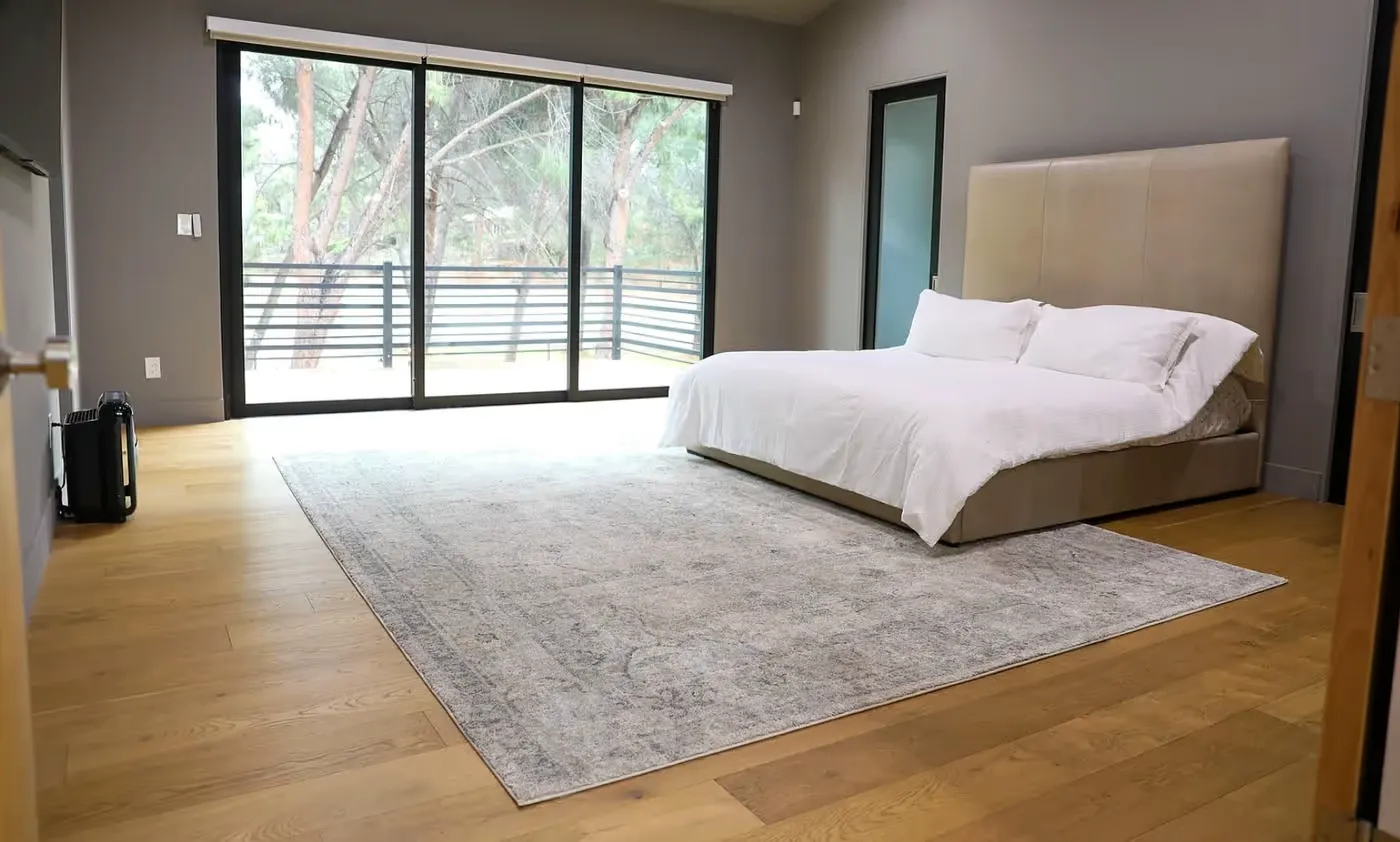 Bedroom with large bed, beige headboard, white bedding and natural light