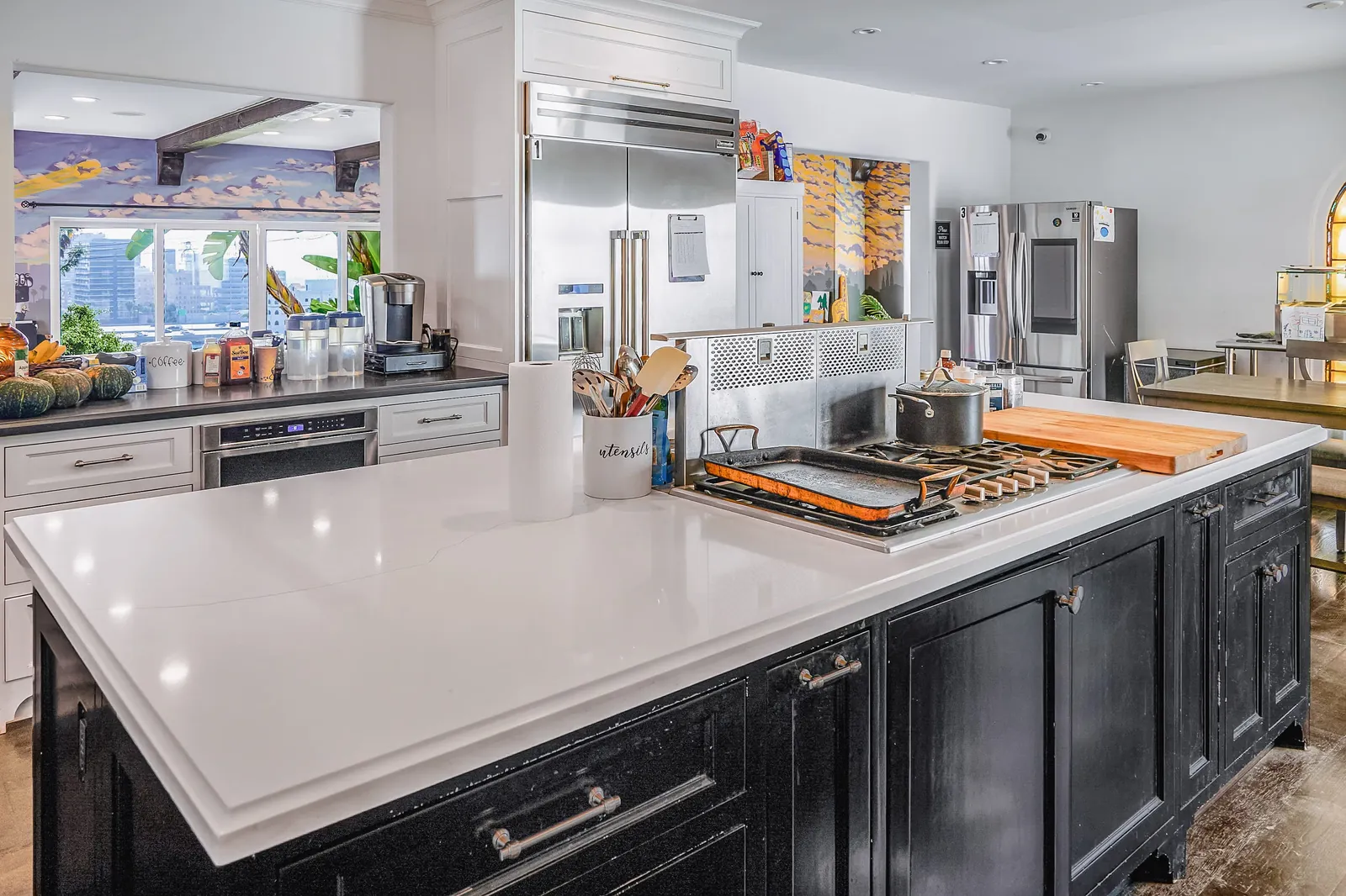 Kitchen with a professional range, black island and a view through to the garden