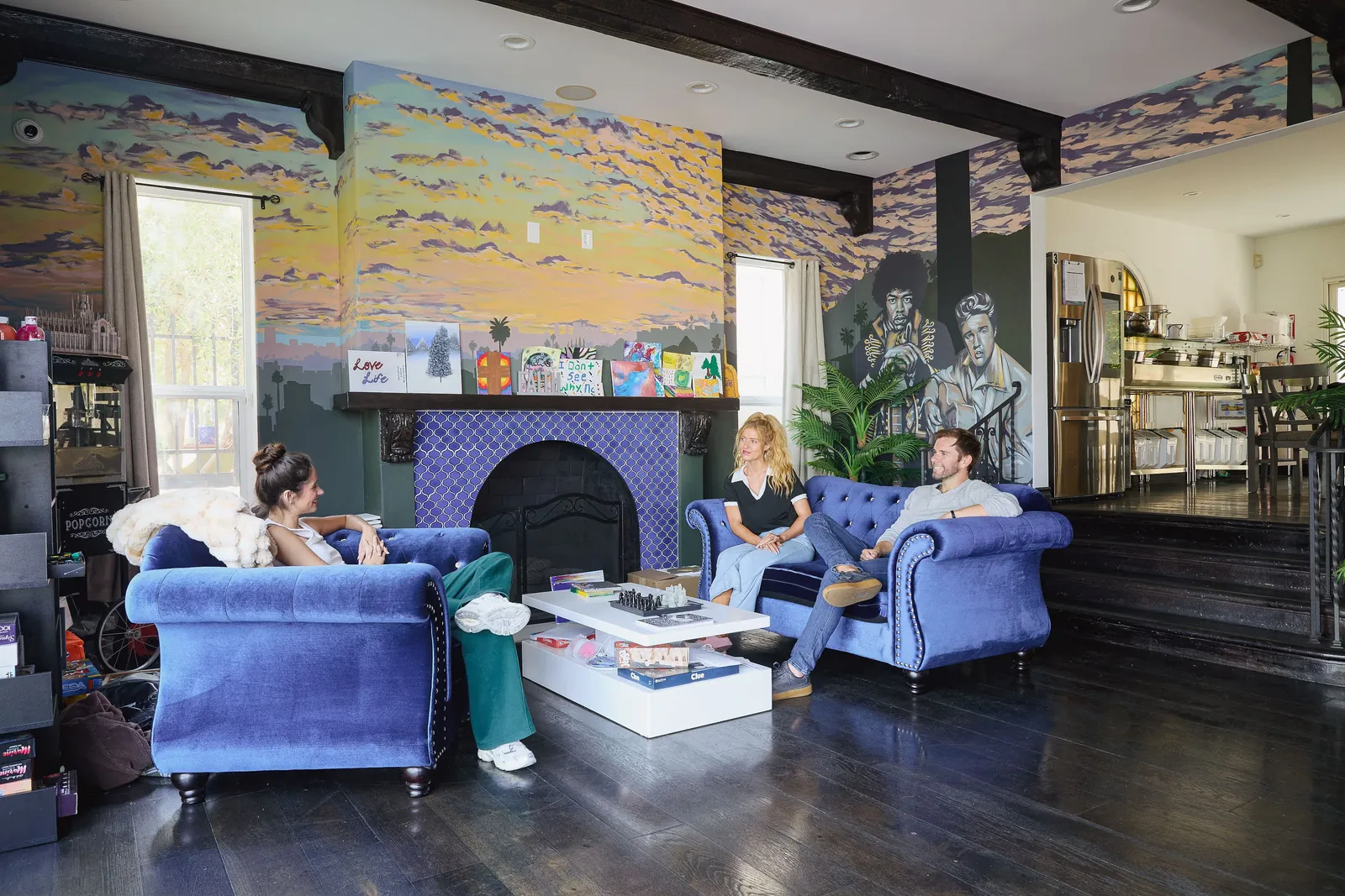 Lounge with blue armchairs and a tiled fireplace, people sitting and talking