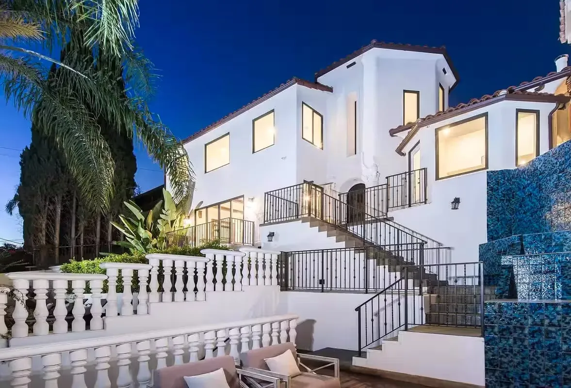 Spanish-style white house at dusk, with palms and a tiled external staircase