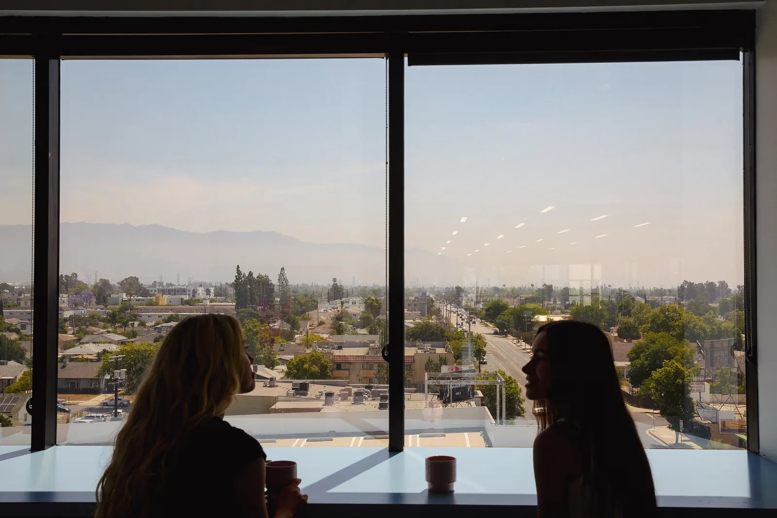 Two people talking at a window overlooking the city