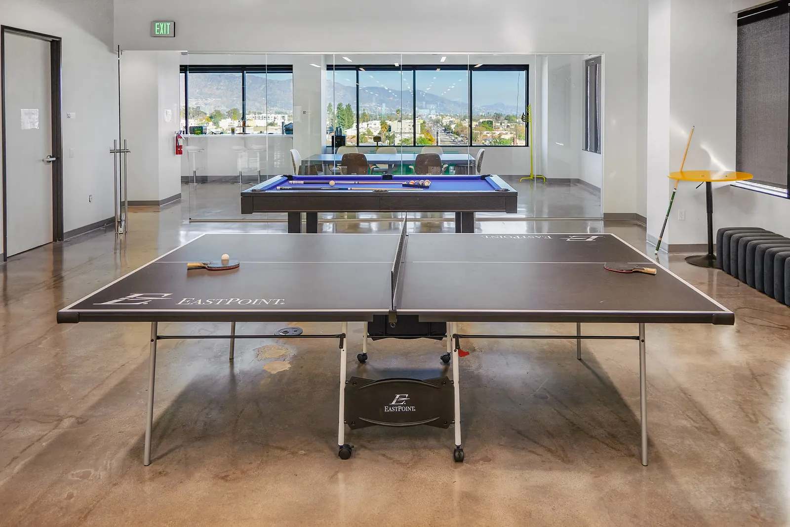 Table tennis table set up beside full-height windows