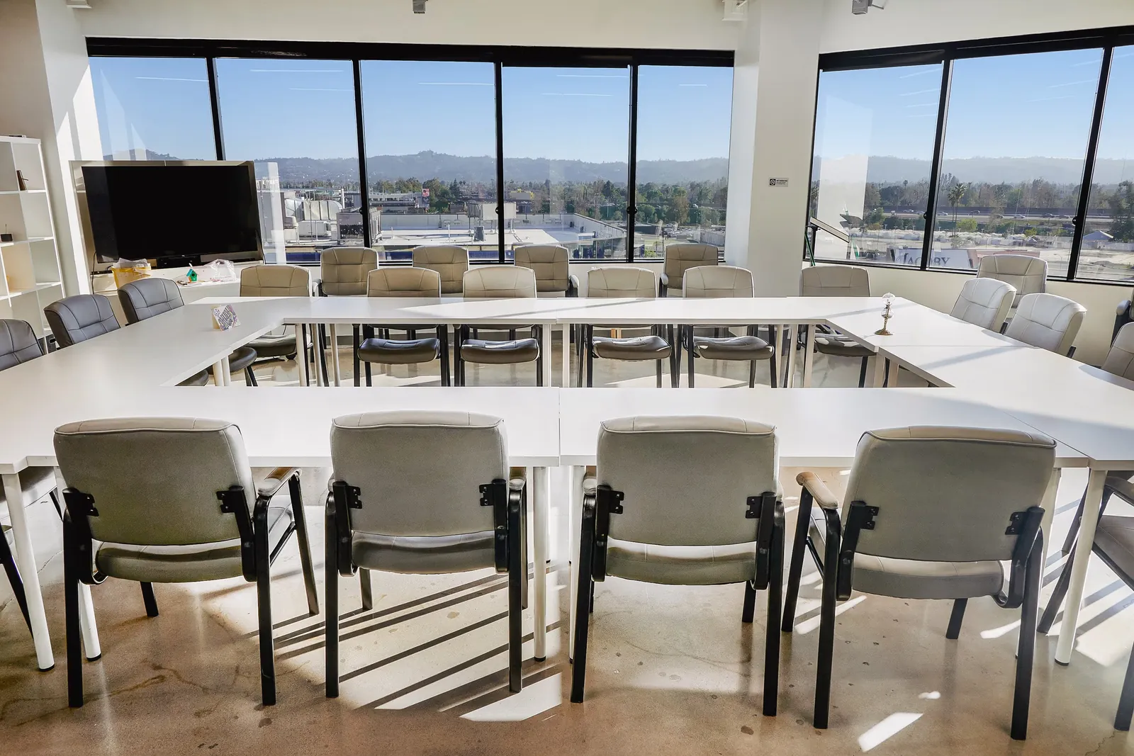 Large group room with a hollow-square table arrangement and a wall-mounted screen