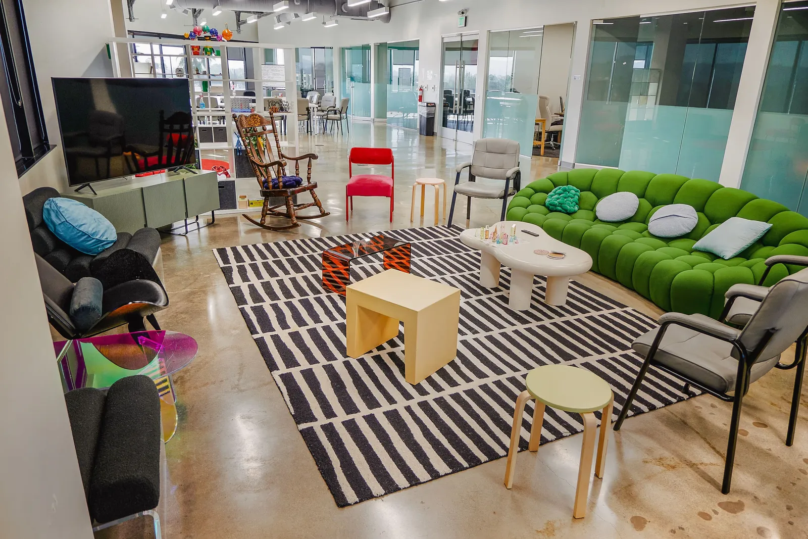 Lounge with a green curved sofa, striped rug and assorted soft seating