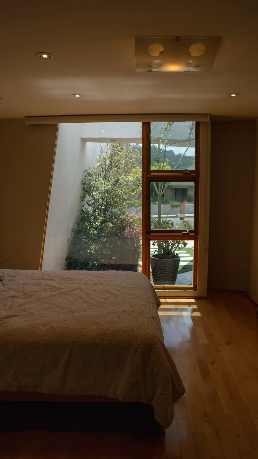 Bedroom with a wide bed and sliding doors opening to a planted garden