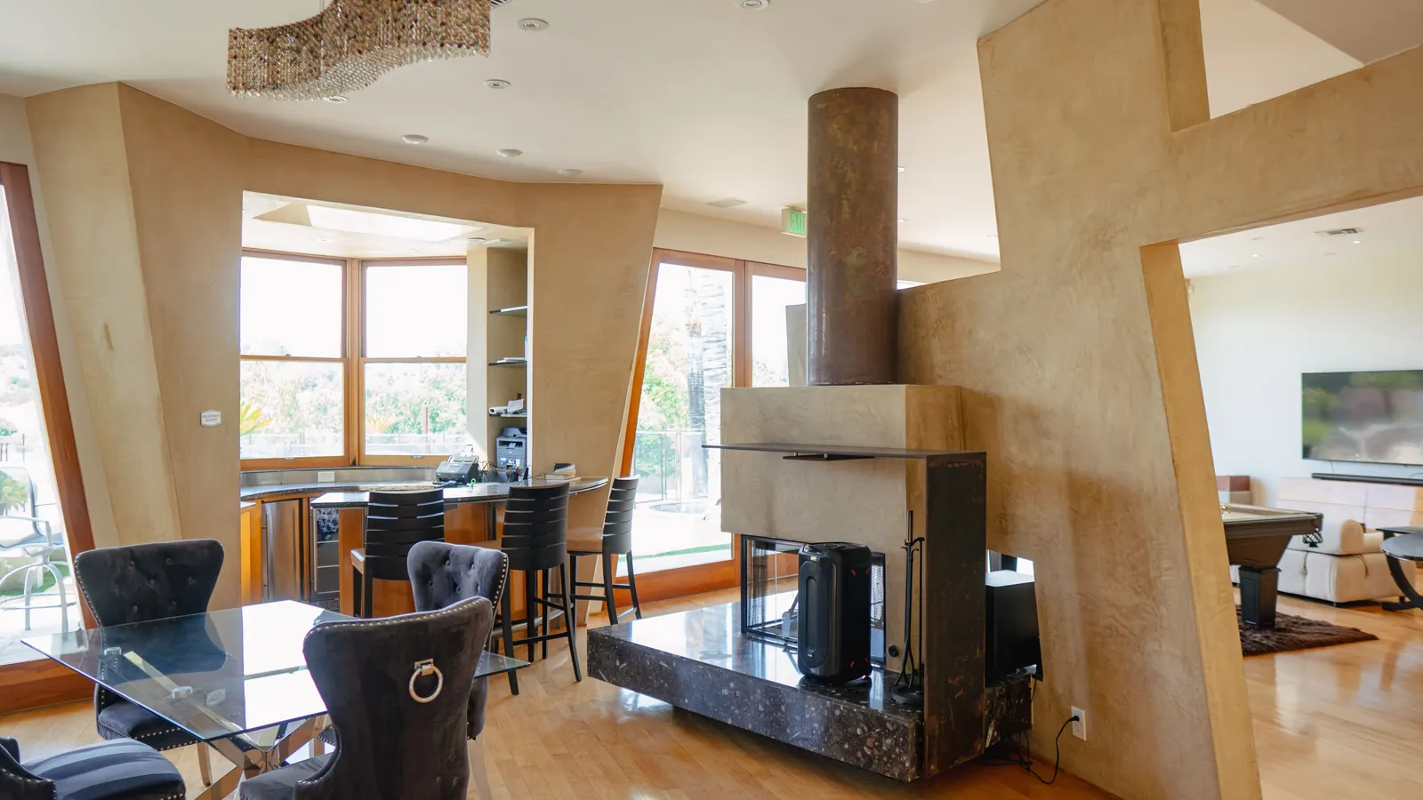 Open-plan living and dining area around a central stone fireplace column