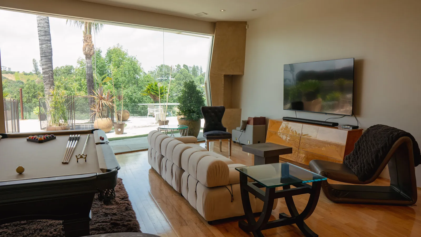 Living room with a full wall of glass looking out to palms and a terrace