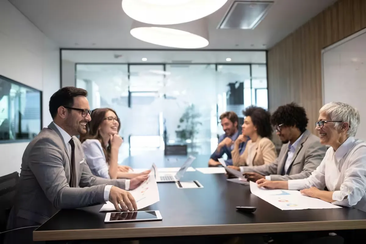 Business professionals meeting around a long conference table in a glass-walled office